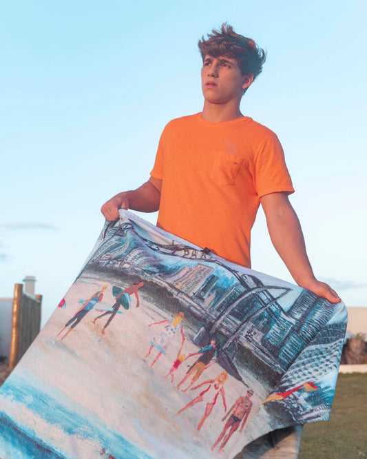 Male model holding Surfers Paradise microfibre artistic towel. The towel shows an art inspiration of the Gold Coast’s suburb of Surfers Paradise. It includes at the beach the famous Surfers Paradise sign, the sea, lifeguards, yellow and red beach safety flag, lifeguard’s tower, surfers, families and kids, beach umbrellas and tall buildings at the back. Large size, 170cm x 95cm, soft touch, compact and sand free beach towel. An Aussie-inspired art showcasing magnificent landmarks and the Aussie lifestyle.